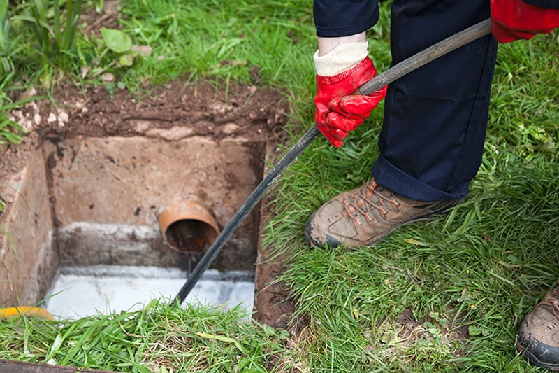 How To Detect a Sewer Line Leak. A plumber unclogging a sewer pipe.