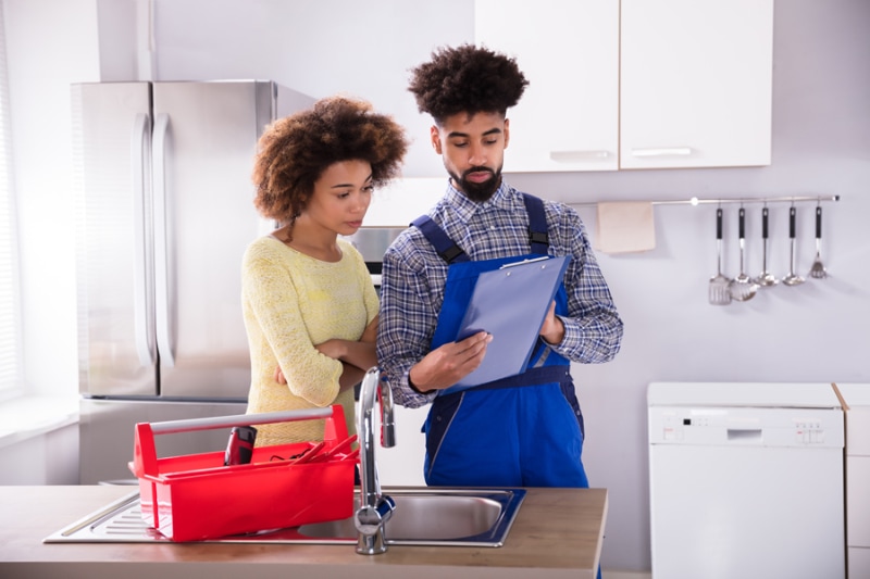 5 Plumbing Maintenance Tips for 2024. Image is a photograph of a plumbing professional reviewing plans with homeowner.